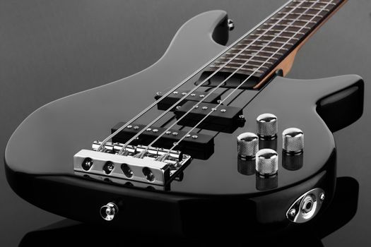 The body of black electric bass guitar on dark background