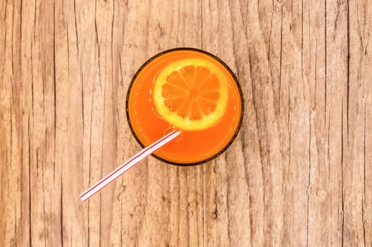 Multifruit juice in a glass with a straw viewed from above on a wooden background