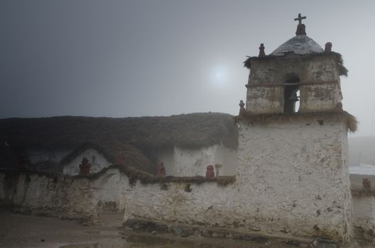 Church and bell tower of Parinacota in a fog. Lauca National Park. Arica y Parinacota Region. Chile.