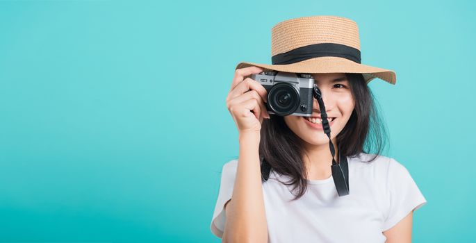 Traveler tourist happy Asian beautiful young woman smile in summer hat standing with mirrorless photo camera, shoot photo in studio on blue background with copy space for text