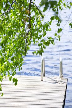 Wooden walkway jetty pier with railing for swimming in lake in Finland