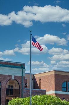 An American flag flying under blue skies  in front of an old brick government building