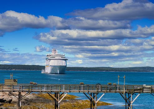 A large luxury cruise ship moored in the bay off of Bar Harbor, Maine beyond an old wood pier