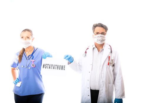 Two medical practitioners, hospital workers hold a sign to encourage strongly community to stay at home to stop the spread of a contagious disease pandemic