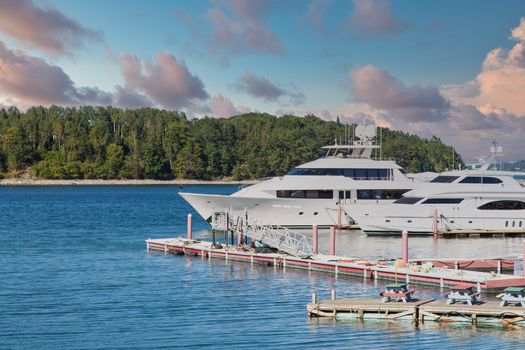 Two white luxury yachts at a pier in a harbor in Maine