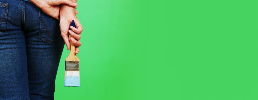 Young woman painting green wall with paint brush and renovating home copy space for text