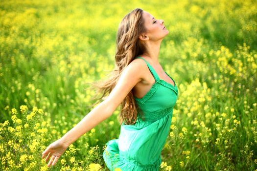 Young woman enjoy life dancing on oilseed flower field