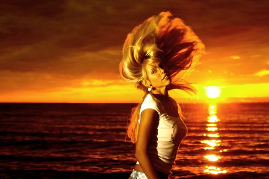 Beautiful girl hair waving motion on golden sunset over sea