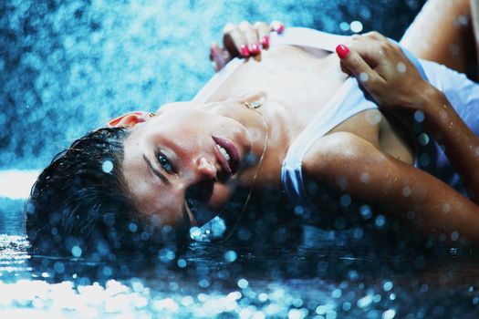 Young sexy woman, water studio photo in blue light