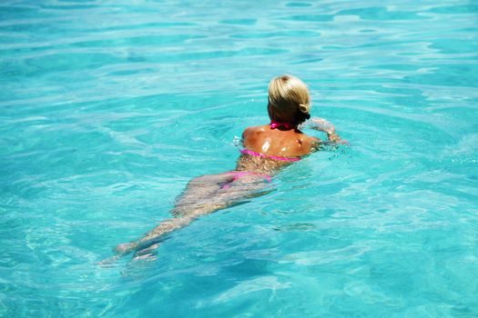 Beautiful woman swim in blue water of sea or swimming pool