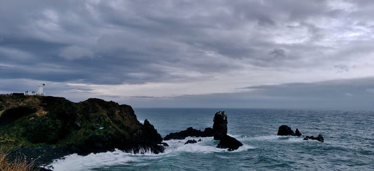 A landscape photo of a lighthouse by the sea.