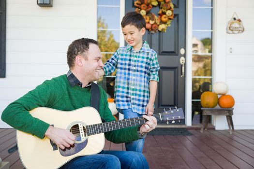 Young Mixed Race Chinese and Caucasian Son Singing Songs and Playing Guitar with Father