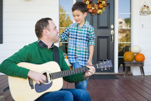 Young Mixed Race Chinese and Caucasian Son Singing Songs and Playing Guitar with Father