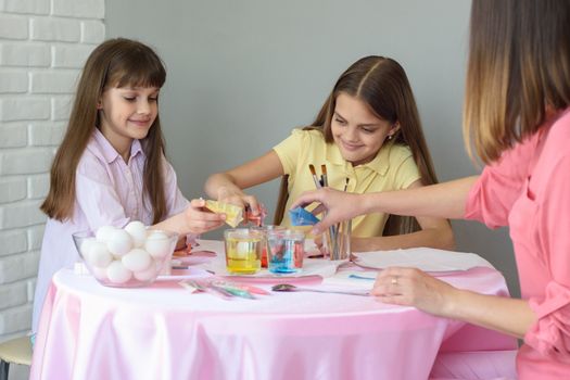 Mom with daughters fall asleep dye for coloring eggs in glasses with water