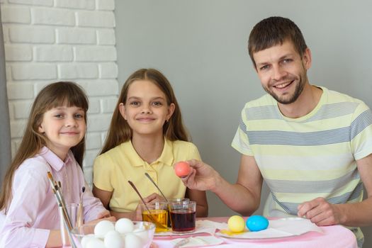 Happy family paints easter eggs at the table and looked joyfully into the frame