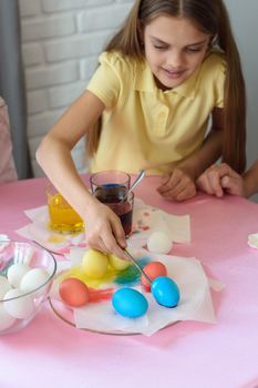 Girl paints Easter eggs in a special solution and puts on a plate