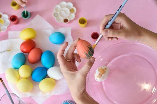 Hand paints a chicken egg on Easter