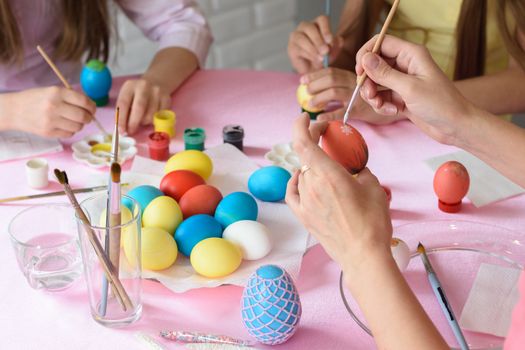 Family decorates chicken eggs on the table for Easter, close-up