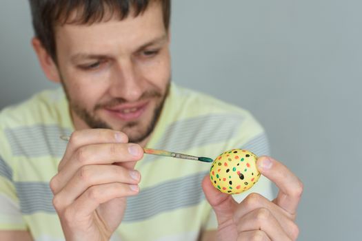 Man paints an egg for Easter