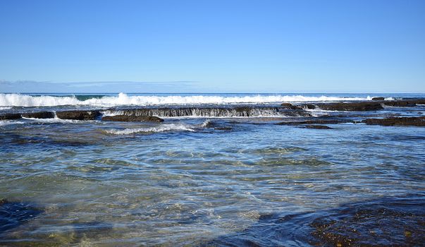 Beach with a crashing wave and rocks