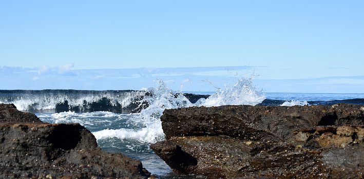 Beach with a crashing wave and rocks