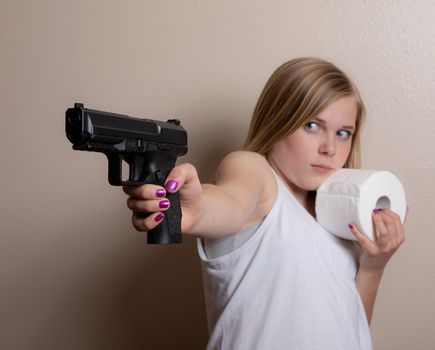 Young girl holds a gun in one hand and her toilet paper in the other