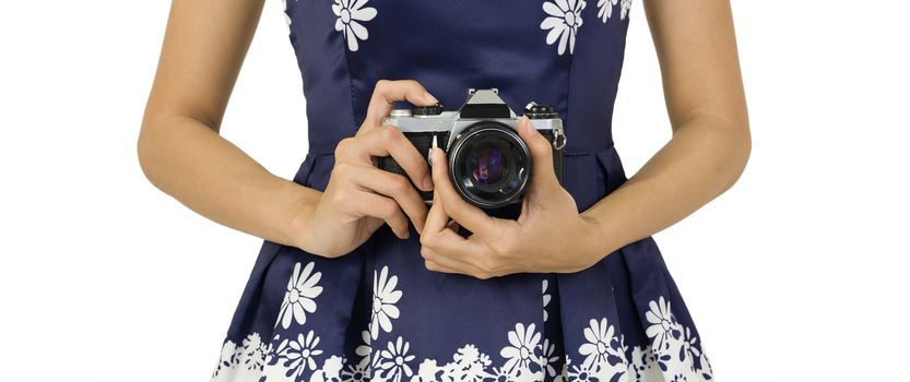 Young traveler in blue dress holds the old camera by hand in the hip position.