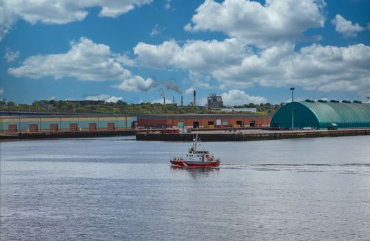 Canadian Coast Guard boat cruising past industrial area on coast of Canada