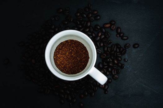 The Top view of Instant coffee in cup on dark background with beans