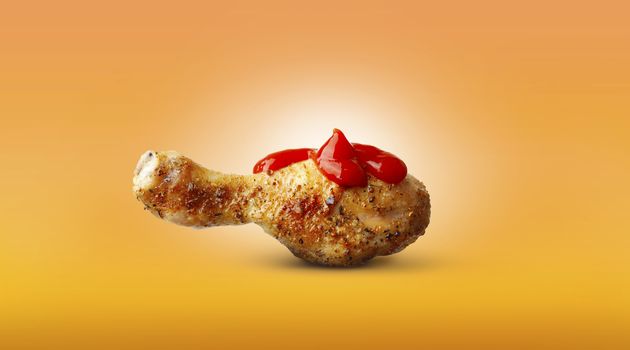 Baked chicken leg ketchup sauce spices isolated on orange background
