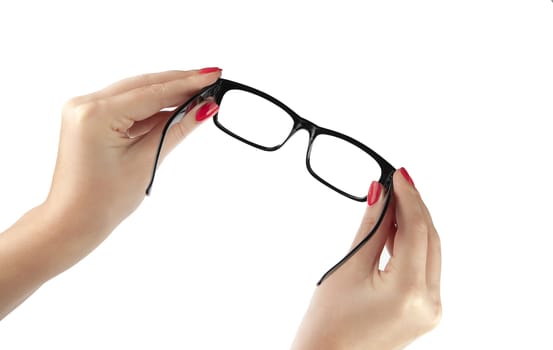 Female hand holding a black-framed glasses isolated on white background