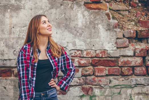 Young beautiful woman is smiling while standing in front of brick wall