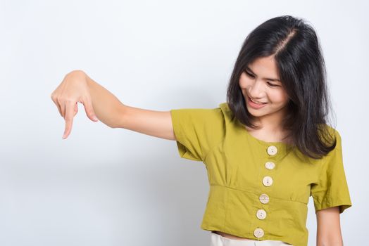 Portrait Asian beautiful young woman standing, She points down to space with fingers and looking to space, shoot photo in a studio on white background, There was copyspace