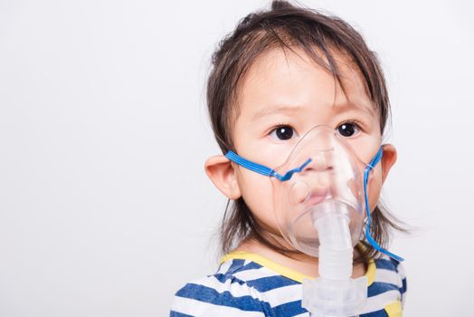 Closeup Asian face, Little baby girl sick her using steam inhaler nebulizer mask inhalation oneself on white background with copy space, health medical care