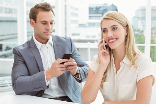 Young business people using mobile phones in office