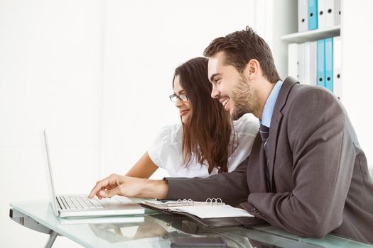 Two young business people using laptop in office