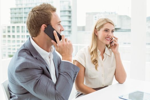 Young business people using mobile phones in office