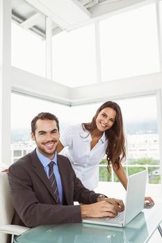 Portrait of two young business people using laptop in office