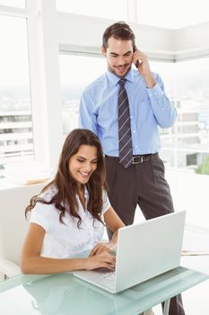 Two young business people using laptop in office