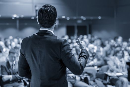 Speaker at Business Conference with Public Presentations. Audience at the conference hall. Entrepreneurship club. Rear view. Panoramic composition. Blue toned greyscale.