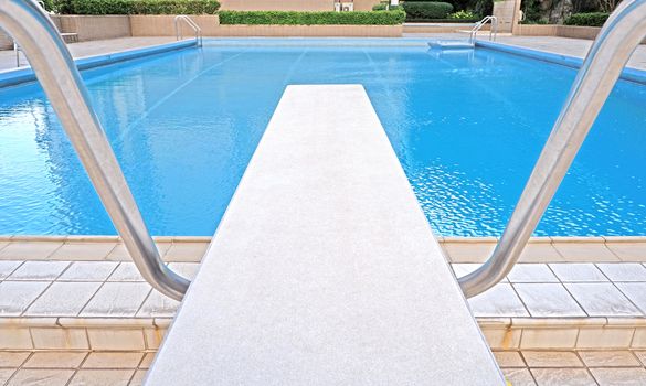 The outdoor private recreational swimming pool with staircase and diving platform at daytime
