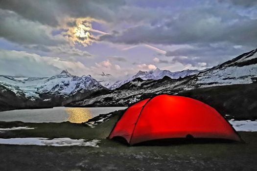 The outdoor camping tent, lake, snow mountain in Switzerland countryside campsite