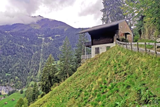 The outdoor countryside house building, mountain, green field, footpath with wooden fence in Switzerland