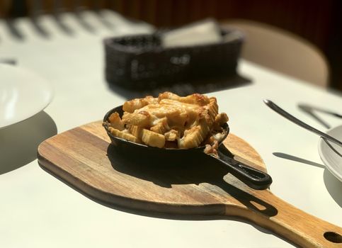 The cooked french fries on pan and wooden dish