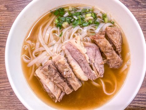 The bowl of Chinese food meat noodles on wooden table
