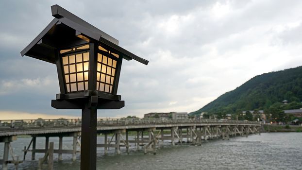 The traditional lamp, mountain, wooden bridge, rapid river in Japan Kyoto