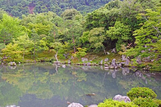 The green plants, trees, mountain, lake with reflection in the Japan zen garden