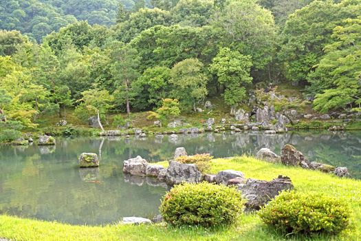 The green plants,  trees, mountain, fish, lake with reflection in the Japan zen garden