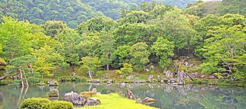 The green plants,  trees, mountain, fish, lake with reflection in the Japan zen garden