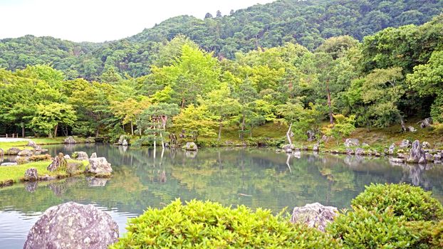 The green plants,  trees, mountain, lake with reflection in the Japan zen garden